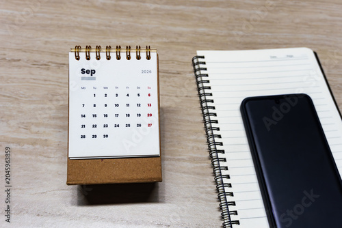 Canvastavla Top view of September 2026 desk calendar with smartphone and blank spiral notebook on wooden table