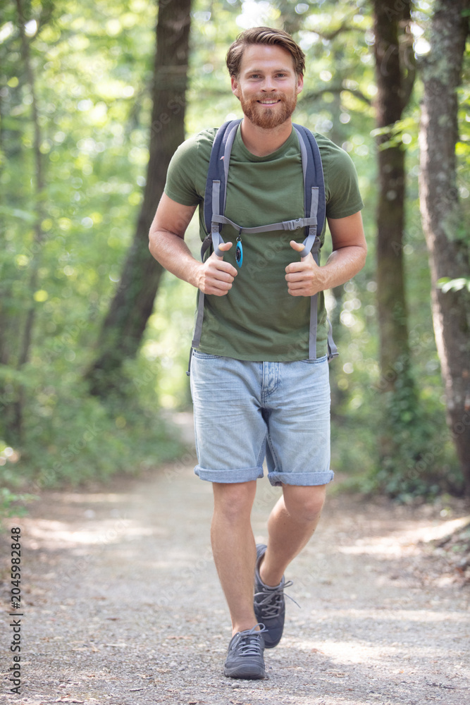 Naklejka premium man wearing a backpack is walking in the woods