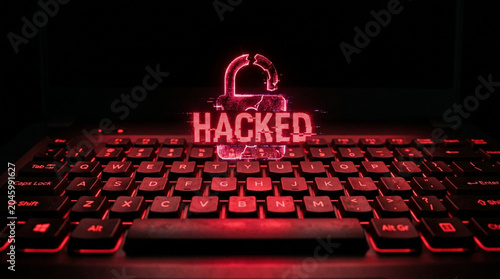 Red glowing digital hologram of a broken padlock and the word HACKED on a backlit laptop keyboard, representing a cybersecurity data breach, system compromise, and computer virus.