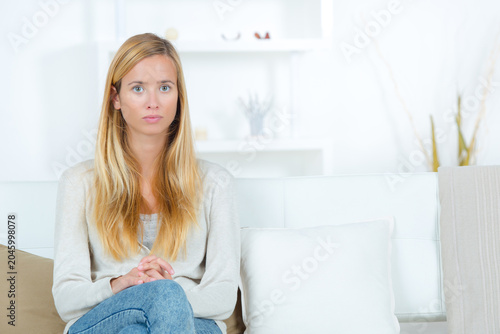 portrait of serious young woman sat alone on sofa