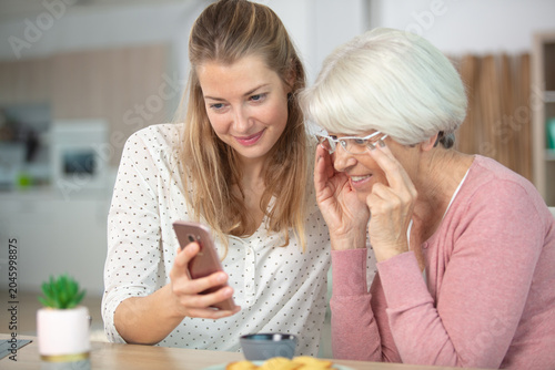 pleasant smiling mother and daughter using cell phone