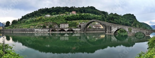 The devil's bridge or Maddalena Bridge, is a historic stone bridge with unique arches, beautifully reflected in the calm green waters of the Serchio River in Borgo a Mozzano, village of Tuscany, It