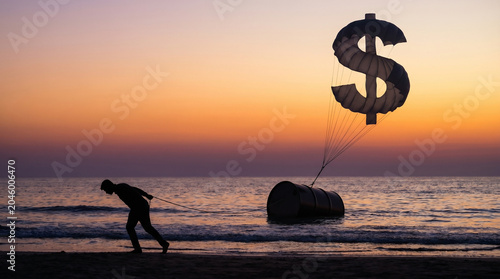 Oil prices soar with silhouette man pulling barrel at sunset