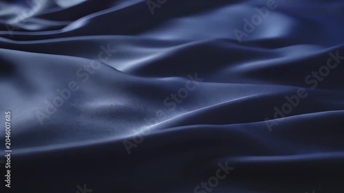 Silk fabric waves in soft dark blue folds creating a luxurious deep texture.