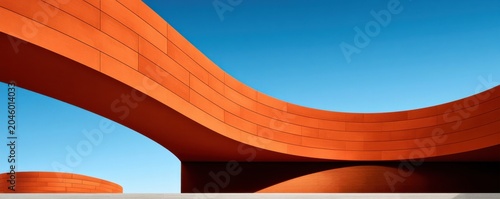 Contemporary curved orange architecture with clean minimalist lines against a clear blue sky