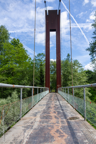Old pedestrian suspension bridge set in lush green area in Asturias, Spain