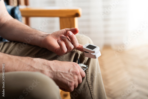 Caucasian middle aged man using pulse oximeter at home