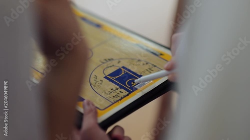 Group discusses basketball strategy in gym with markers and clipboard