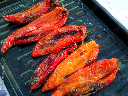 Bild auf Leinwand Salted and oiled red romano peppers ready grilled on a black sheet on a gas grill being grilled for a vegetarian meal