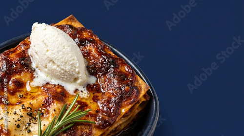 Gourmet Lasagna Slice with Ricotta Cheese and Rosemary on Dark Blue Background