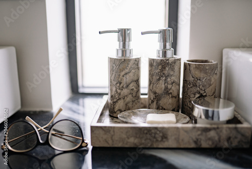Quadro su tela Bathroom countertop displaying elegant marble soap dispensers, bar soap, a tumbl