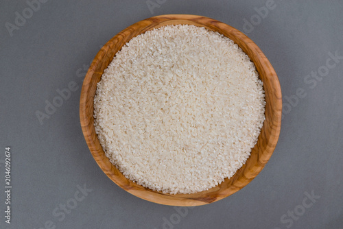 Schilderij op canvas Cuenco de madera lleno de arroz sobre fondo gris