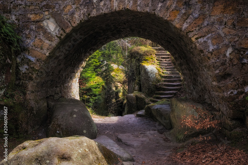 Stone archway leading to forest path and stairs