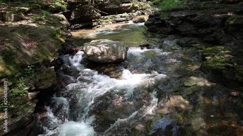 Closeup of water flowing around a large boulder in a forest stream