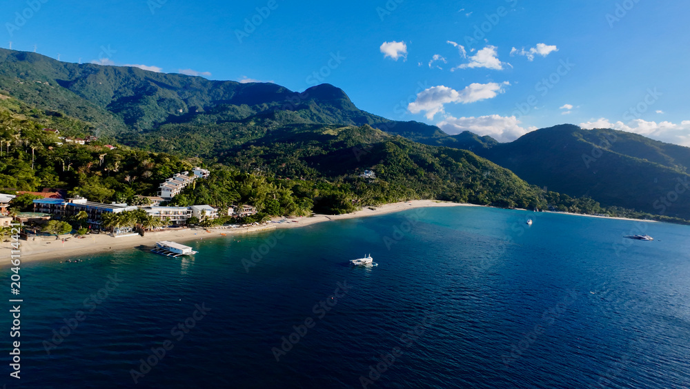 Obraz premium Tropical resort coastline in Asia. Aerial view of a popular beach destination with turquoise waters, white sand and lush mountains.