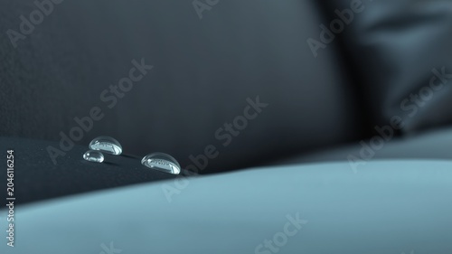 Close-up of water droplets on a dark-colored, water-resistant surface demonstrating excellent liquid repellency