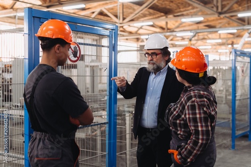 Foto Foreman instructing workers in factory production area