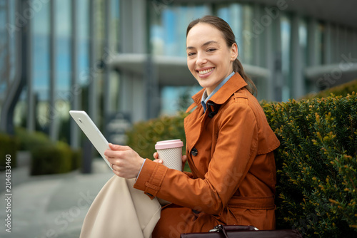 Professional woman smiling holding tablet and coffee cup