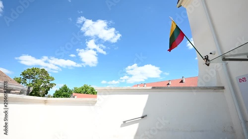 The vibrant Lithuanian flag proudly flutters against a bright blue sky filled with white clouds, showcasing national pride and a beautiful day in the historic city of Vilnius, Lithuania