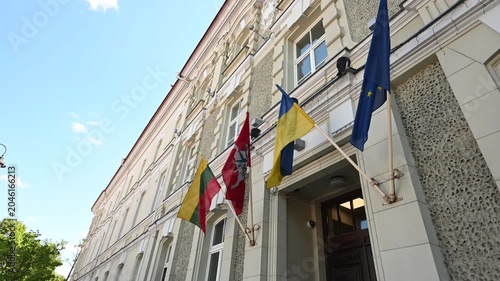 Lithuanian, Ukrainian, and European Union flags flying proudly on a sunny day from a historic building in Vilnius, Lithuania, symbolizing international unity and support.