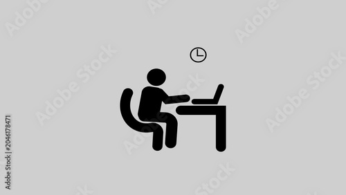 Black silhouette of person sitting at desk with laptop and clock above