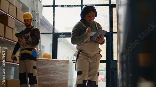 Fotografie Relaxed african american warehouse picker listening music while checking labels on cardboard boxes