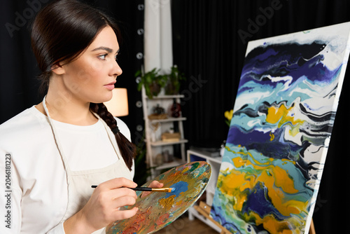 Tableau sur toile Creative moments of a beautiful young woman painting in her cozy home studio