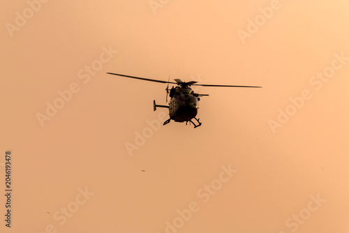 Silhouette helicopter flying towards me on isolated sky during dawn
