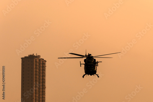 Silhouette helicopter flying towards me on isolated sky during dawn