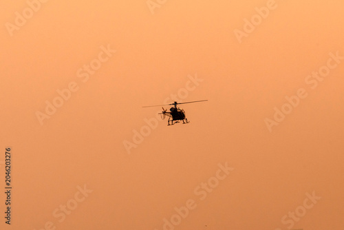 Silhouette helicopter flying towards me on isolated sky during dawn