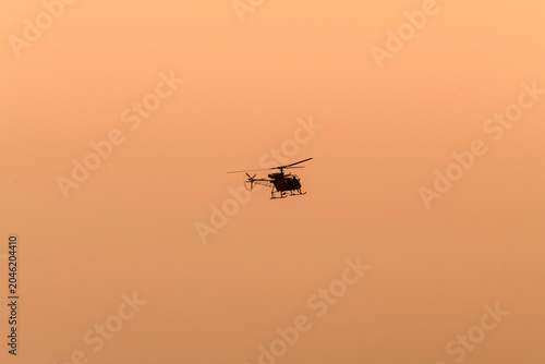 Silhouette helicopter flying towards me on isolated sky during dawn