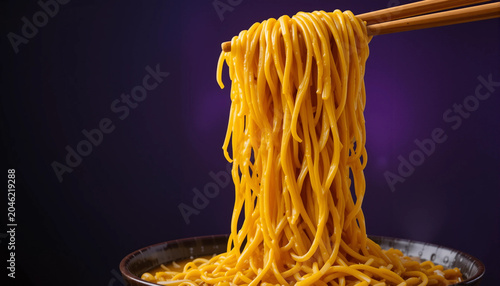 Bowl of yellow noodles lifted with chopsticks against a purple background highlights the texture of the strands and the smooth curve of the bowl rim.