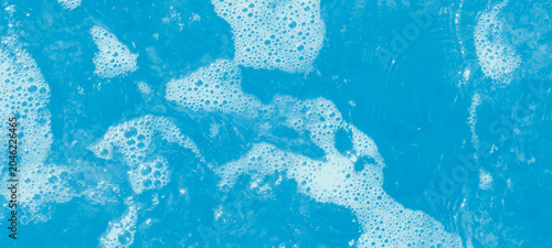 Schilderij op canvas Bright blue ocean water surface with frothy white bubbles and shimmering sunligh