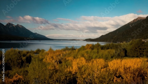 Scenic landscape featuring a serene lake surrounded by mountains and foliage.