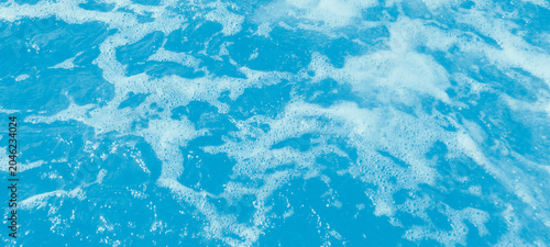 Foto Abstract texture of turbulent blue water surface with white sea foam bubbles, ri