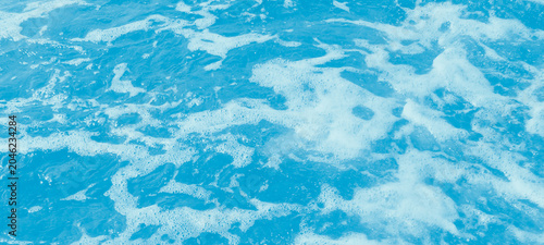 Foto Abstract texture of turbulent blue water surface with white sea foam bubbles cre