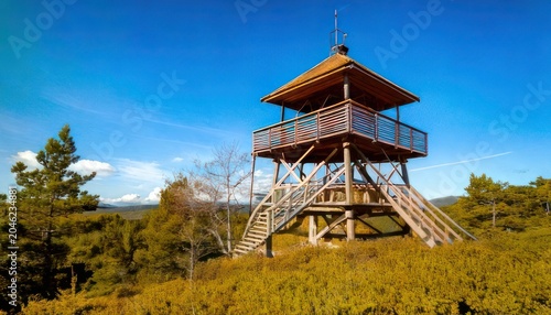 Scenic Lookout Tower on Hilltop Under Blue Sky - A Natural Landscape.