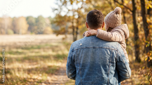 Father Carrying His Little Daughter on Arms from Behind in Autumn Park for Father's Day