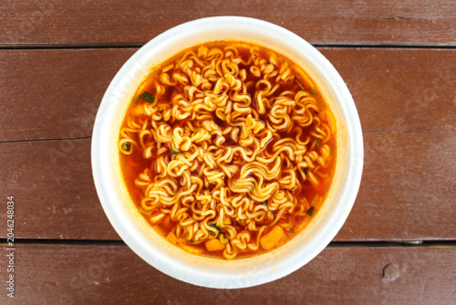 Hot spicy instant cup noodles with chopsticks in a disposable bowl and steaming red broth ready to eat, showcasing popular Korean convenience food and quick meal culture.
