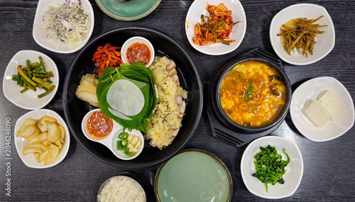 Traditional Korean bossam set meal with boiled pork slices, soybean paste stew, fresh vegetables, kimchi, rice, and assorted side dishes served on a dining table.