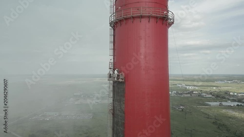 Industrial alpinism,industrial climbing Painters Coating Tall Chimney Stack at Industrial Facility Maintenance and Restoration Work at Height.Professional industrial painters performing maintenance