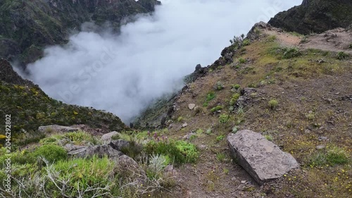 Tilt up shot of misty volcanic valley below clouds on PR1 trail, Madeira