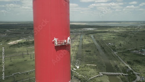 Industrial alpinism,industrial climbing Painters Coating Tall Chimney Stack at Industrial Facility Maintenance and Restoration Work at Height.Professional industrial painters performing maintenance