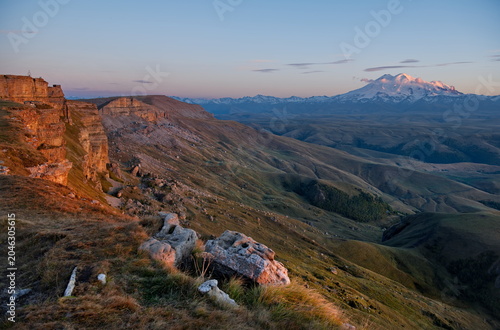 Russia, Elbrus region. Sunset on the rocks of the Bolshoy Bermamyt plateau against the backdrop of Mount Elbrus.