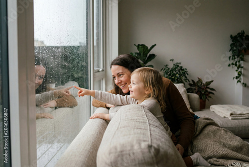 Mother and Daughter Looking at Rain Through Window at Home