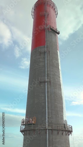 Industrial alpinism,industrial climbing Painters Coating Tall Chimney Stack at Industrial Facility Maintenance and Restoration Work at Height.Professional industrial painters performing maintenance