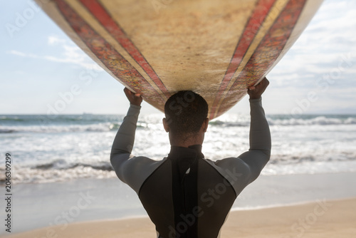 Canvas-taulu Surfer carrying board oceanfront photo