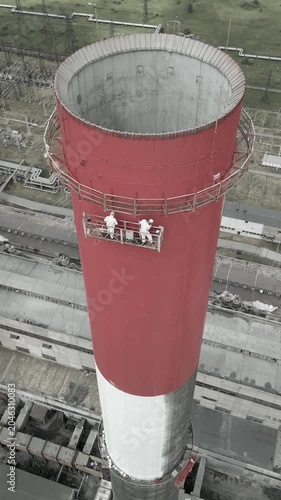 Industrial alpinism,industrial climbing Painters Coating Tall Chimney Stack at Industrial Facility Maintenance and Restoration Work at Height.Professional industrial painters performing maintenance