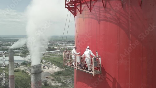 Industrial Painters Coating Tall Chimney Stack at Industrial Facility.Work at Height.Concept of industrial maintenance,occupational,infrastructure renovation,engineering services,construction industry