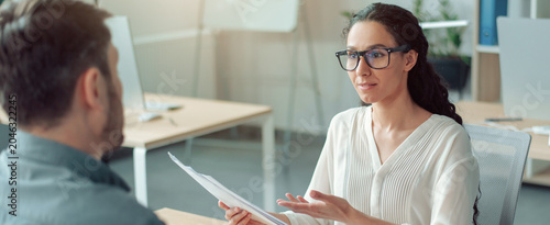 Cuadro en lienzo Focused Young Hispanic Woman Interviewing Male Candidate In Modern Office, Discussing Job Position And Application Details